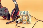 Black headphones and 100 dollar bills. Tan background.