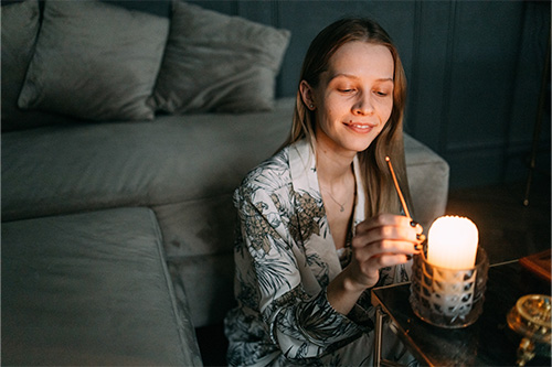 Woman lights scented candle to benefit her meditation. Woman lights scented candle to benefit her meditation.