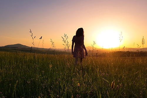 Woman walking toward sunrise. Your new life is here. Woman walking toward sunrise. Your new life is here.