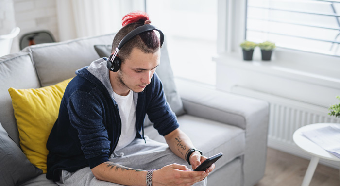 Gen Z seeks success using theta waves. Gen Z guy with iPhone and headphones.