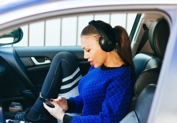 Woman in car with headphones listening to Audible. Woman in car with headphones listening to Audible.