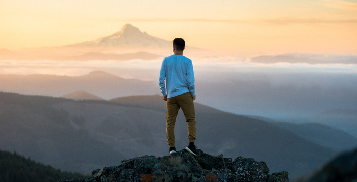 Man on mountaintop comptemplating wealth manifestation.