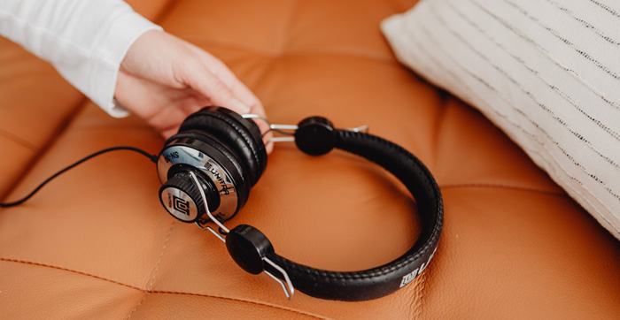 Hand holding headphoneson luxury couch for Amazon Audible listening. Hand holding headphoneson luxury couch for Amazon Audible listening.