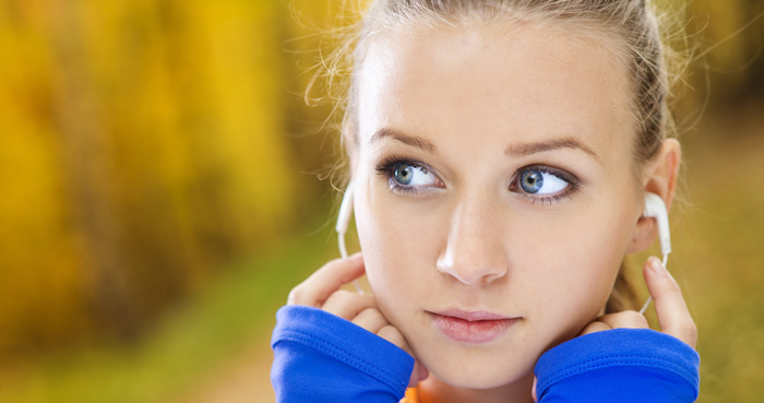 Young woman listening to Amazon Audible audiobooks with ear buds. Young woman listening to Amazon Audible audiobooks with ear buds.