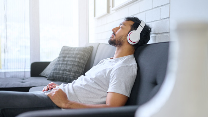 Man relaxing by listening to binaural beats to elevate his creativity.
