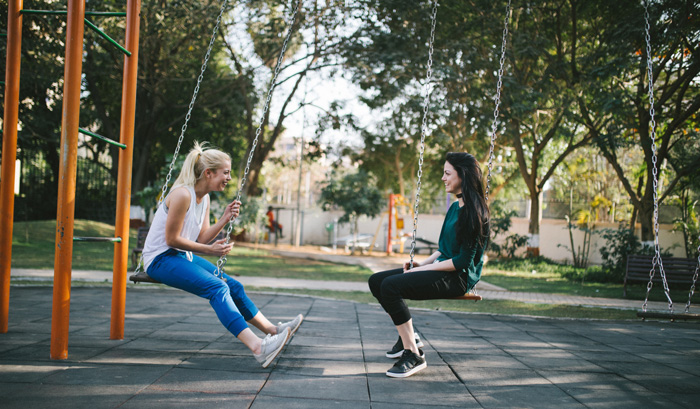 Two women on playgoround swings Two women on playgoround swings