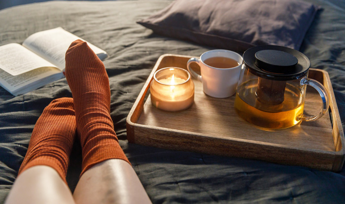 Women writers and scented candles. Legs on bed with candle and tea. Women writers and scented candles. Legs on bed with candle and tea.