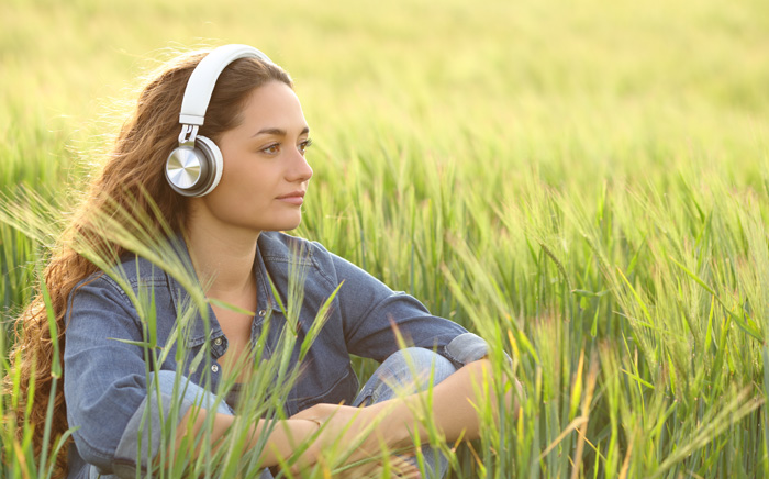 Young woman writer in tall grass listening to binaural beats. Young woman writer in tall grass listening to binaural beats.