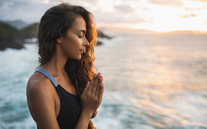 Woman paying on a rugged coast. Woman paying on a rugged coast.