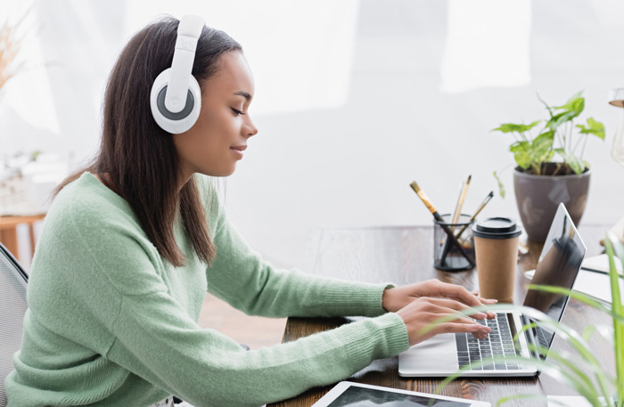Young African-American writer listening to Amazon Audible binaural beats to enhance her creativity and focus.
