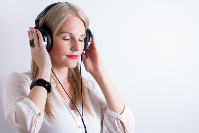 Woman writer listens to binaural beats to create theta waves before her writing session. Woman writer listens to binaural beats to create theta waves before her writing session.