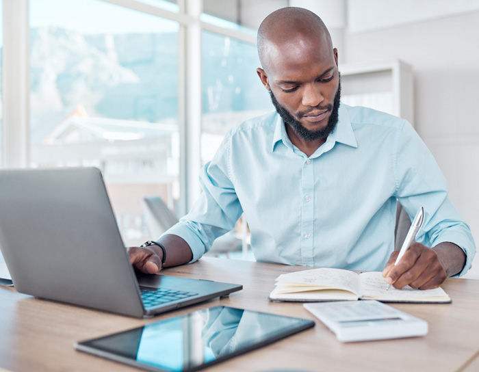 Get fucking rich. African American man studying investment strategies on his laptop. Get fucking rich. African American man studying investment strategies on his laptop.