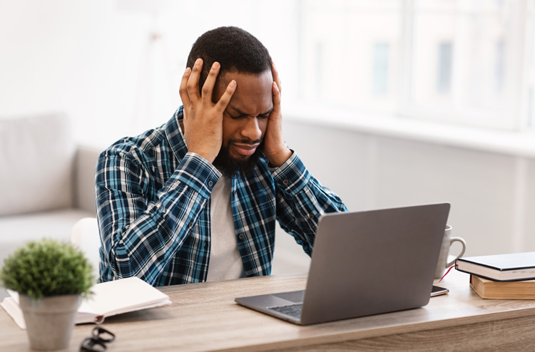 Young African-American guy frustrated with mistake he made on his laptop.