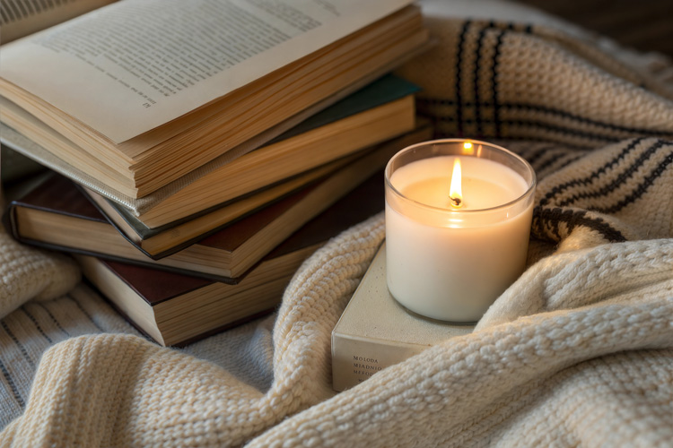 Candle, books, and blanket for a woman writer.