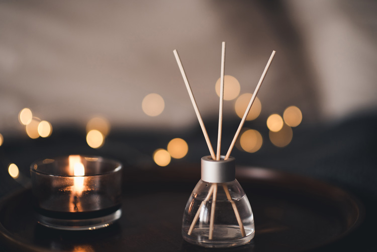 Essential oils diffuser with bamboo sticks and a small candle.