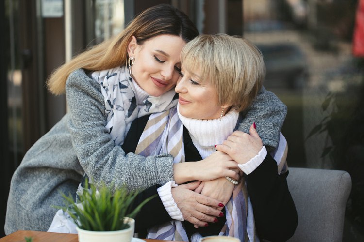 Adult woman hugs her senior mother.