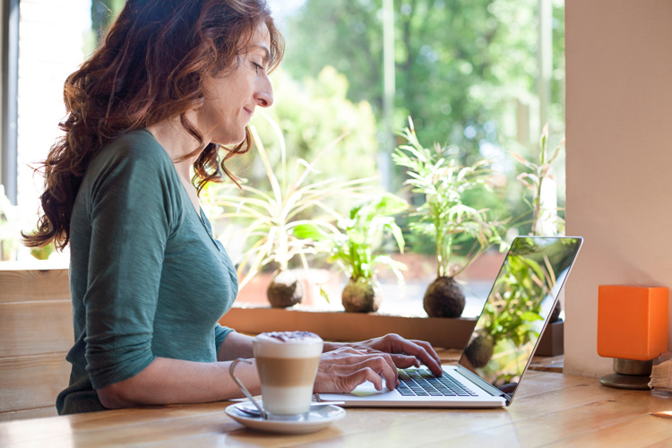Young woman writer with her laptop in a budget-friendly zen writing room she created.
