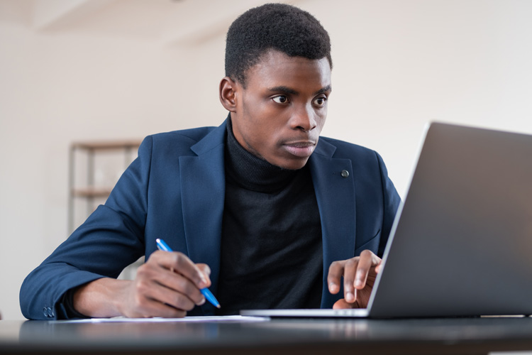 Young African-American man working hard on laptop for his future business
