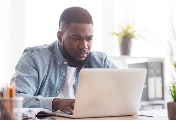 Young African-American man taking action on his laptop to get ahead.